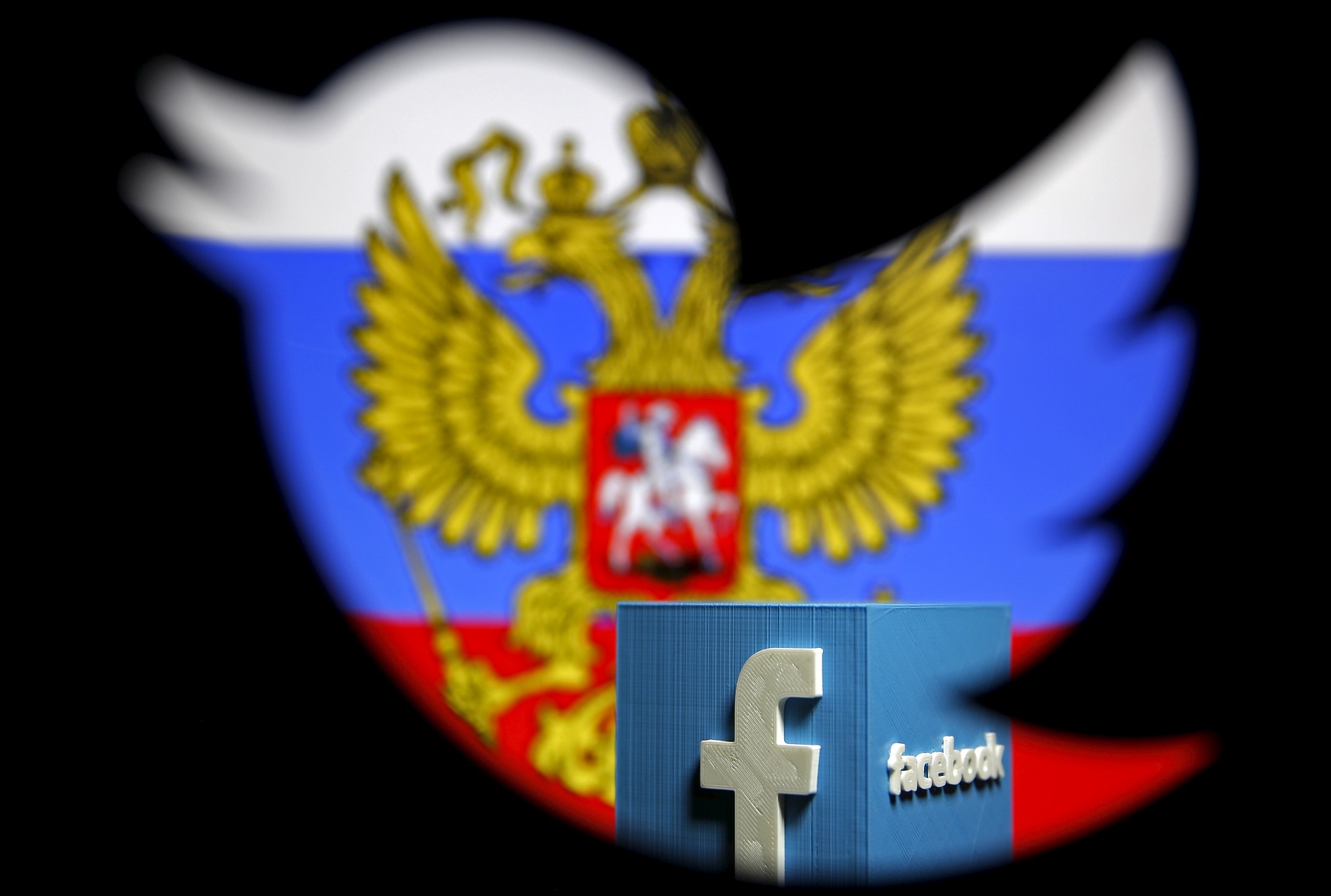 A Russian flag and a 3D model of the Facebook logo is seen through a cutout of the Twitter logo in this photo illustration taken in Zenica